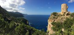 Aerial view of picturesque Mallorca coastline with clear blue water, rocky cliffs, and lush greenery