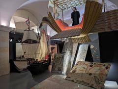 Exhibits at Lisbon Story Centre showcasing a large model ship and Bartolomeu Lourenço de Gusmão's Passarola aircraft with maps of Lisbon, Africa, and South America