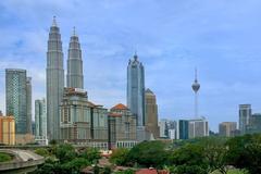 skyline of Kuala Lumpur at dusk with prominent landmarks like the Petronas Twin Towers