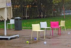 people rushing indoors due to sudden rain outside Tate Modern, scattered paper cups and chairs on the ground