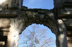 Temple of Diana in Nîmes with stone arch and surrounding greenery