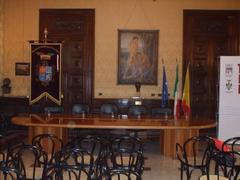 Sala Sciascia in a library with bookshelves and a portrait on the wall