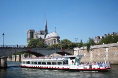 Notre Dame Cathedral view from Quai de Montebello with a tourist boat on the Seine River and Archevêché Bridge