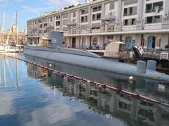 Submarine in Genova harbor with coastal buildings in the background