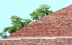 A single red brick embedded in a wall of weathered grey bricks