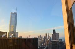 Chicago skyline at golden hour with Trump Tower reflecting the Aon Center and John Hancock Center lit up green