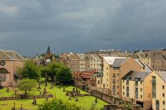 View of Edinburgh cityscape with historic buildings, Arthur's Seat, and blue sky