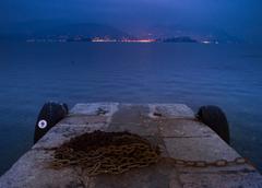 A dock on a lake at dusk with mountains in the background