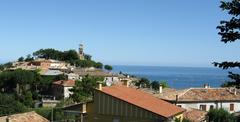 View of Fiorenzuola di Focara village with lush greenery and sea in the background