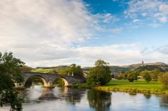 Old Stirling Bridge over a calm river with reflections, surrounded by greenery in Stirling, Scotland