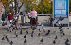 Feral pigeons flying in front of a pink statue at Porte de Hal, Brussels