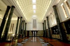 Main lobby of Museum Bank Indonesia with tall pillars, stained glass windows, and revolving doors on both ends