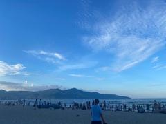 Beautiful Da Nang beach with white sand, calm waves, clear blue water, and shaded coconut trees