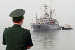 A member of the Vietnam People’s military observing USNS Safeguard steam into Da Nang