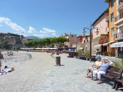 Sunny beach in Collioure with colorful buildings and hill in the background