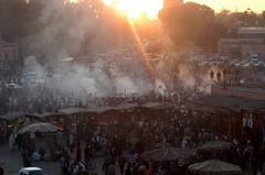 Djemaa el Fna evening market in Marrakech with food stalls and people gathered around entertainers