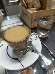 Neapolitan coffee served in a white cup with a glass of water on the side