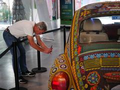 Huichol beaded VW Beetle at Museo de Arte Popular with visitor taking photos