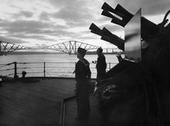 silhouetted eight-barrelled two-pounder 'pom-pom' gun on HMS Rodney at sunset