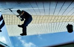 Museum staff washing the large facade glasses of MAAT in Belem, Lisbon from an unusual perspective