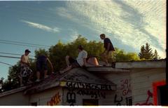 Four teenage boys on a graffiti-covered house roof