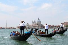 Gondoliers navigating in the Bacino di San Marco off the Punta della Dogana in Venice, Italy