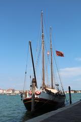 historic sailing ship with Venetian flag docked at Punta della Dogana in Venice