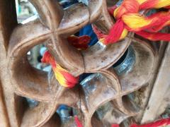 Close-up of sacred threads tied at the window of Nizamuddin Dargah during evening with devotees in the background