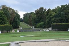 A panoramic view of Domaine national de Marly with lush green lawns and historical architecture under a clear blue sky