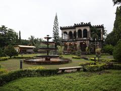 The Ruins mansion in Talisay City with fountain under cloudy sky