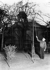 Person lighting a gas lamp in Vanha Kirkkopuisto, black and white photo