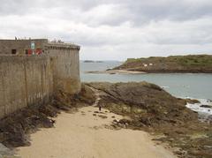 view of Saint Malo's coastline with historical buildings, boats, and beachgoers