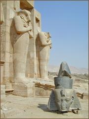 Osirian pillars in the second courtyard of the Ramesseum with a colossal head of Ramses II