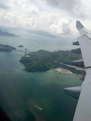 Airplane landing at Hong Kong International Airport with cityscape in the background