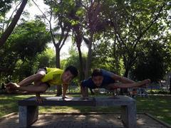 Person performing Astavakrasana yoga pose in an outdoor park