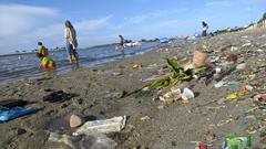 Tourists playing on a trash-filled beach at Ancol