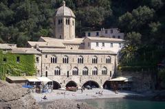 San Fruttuoso Abbey, a historic abbey located in Camogli, Liguria, Italy, surrounded by lush greenery and a clear blue sea.