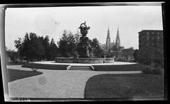 statue with fountain in park, cathedral in background