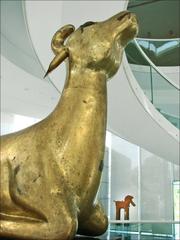 Sculpture of a deer partially visible, made of hammered copper and gilded with mercury amalgam