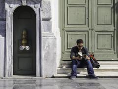 Man reading near a yellow door in Athens