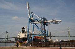 Topflight cargo ship being loaded with a traditional crane near the Walt Whitman bridge