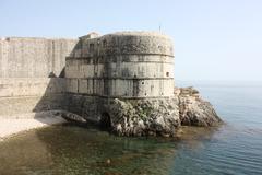 Scenic view of Dubrovnik's Old Town with terracotta rooftops, ancient city walls, and the Adriatic Sea in the background