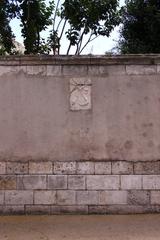 Carved funerary emblems on a stone block in a wall