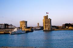 L'avant-port de La Rochelle at sunset with Tour Saint-Nicolas, Tour de la Chaîne, and L'Ilienne ferry