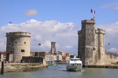 A sightseeing boat leaving the Port of La Rochelle, passing between the Chain Tower and Saint-Nicolas Tower