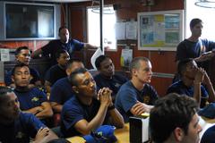 U.S. Navy and Republic of Indonesia Navy divers observe a video on the history of U.S. Navy salvage and recovery operations on USNS Safeguard.