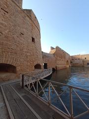 Castello Alfonsino in Brindisi, Italy, surrounded by the sea and partially covered in foliage