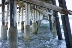 A view under Newport Pier with sunlight reflecting on the water