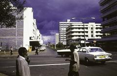 street with modern apartment buildings, pedestrians, Sikh with white turban, cars in Nairobi, Kenya