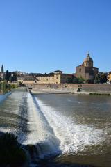 Arno River flowing through Florence with buildings and a bridge visible in the background